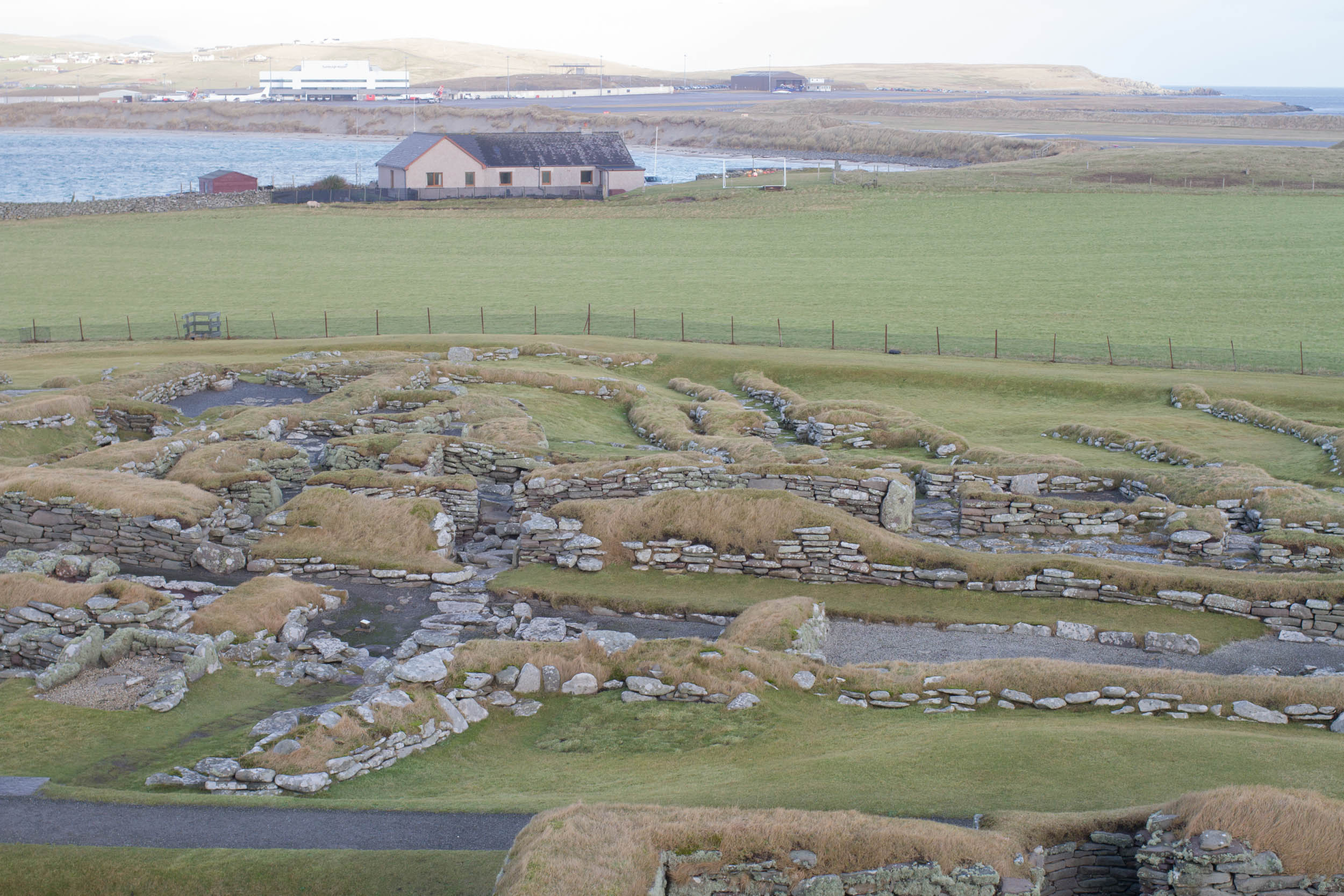 Photo of Jarlshof. A prehistoric and Norse site in Shetland. Remains of a long house - stones showing in the grass