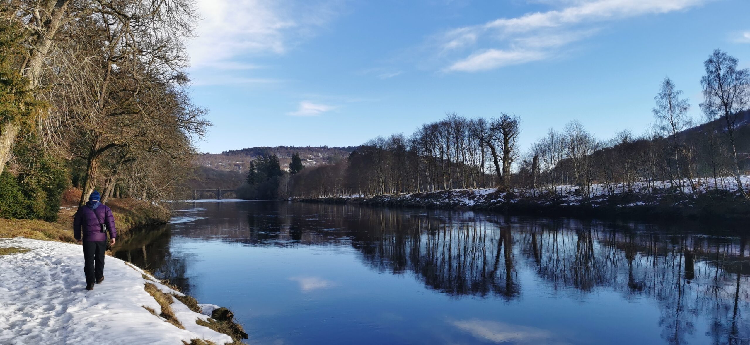 Photo of: the river Tay. A man walking beside the river in snow