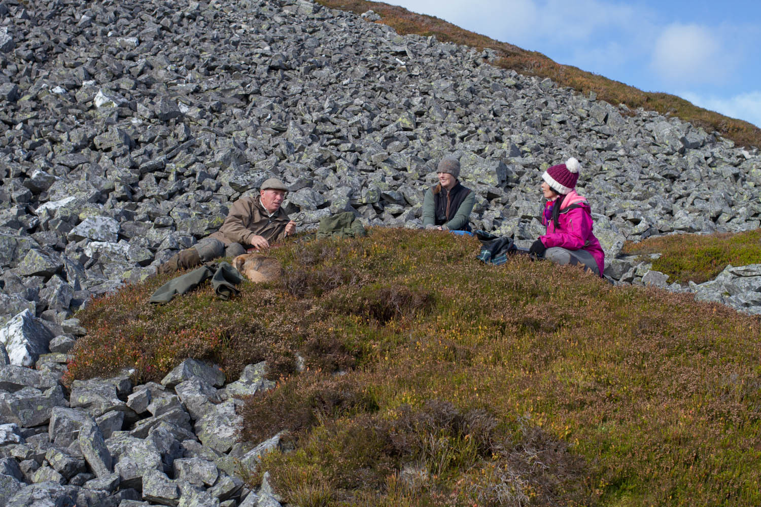 Glenesk Wildlife tours, Scotland. Three people and a dog sat on the heather hills