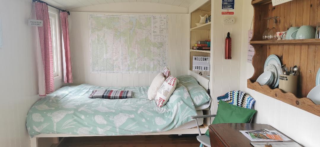 Image of the inside of Creeside Escape. A bed along one wall with shelves behind