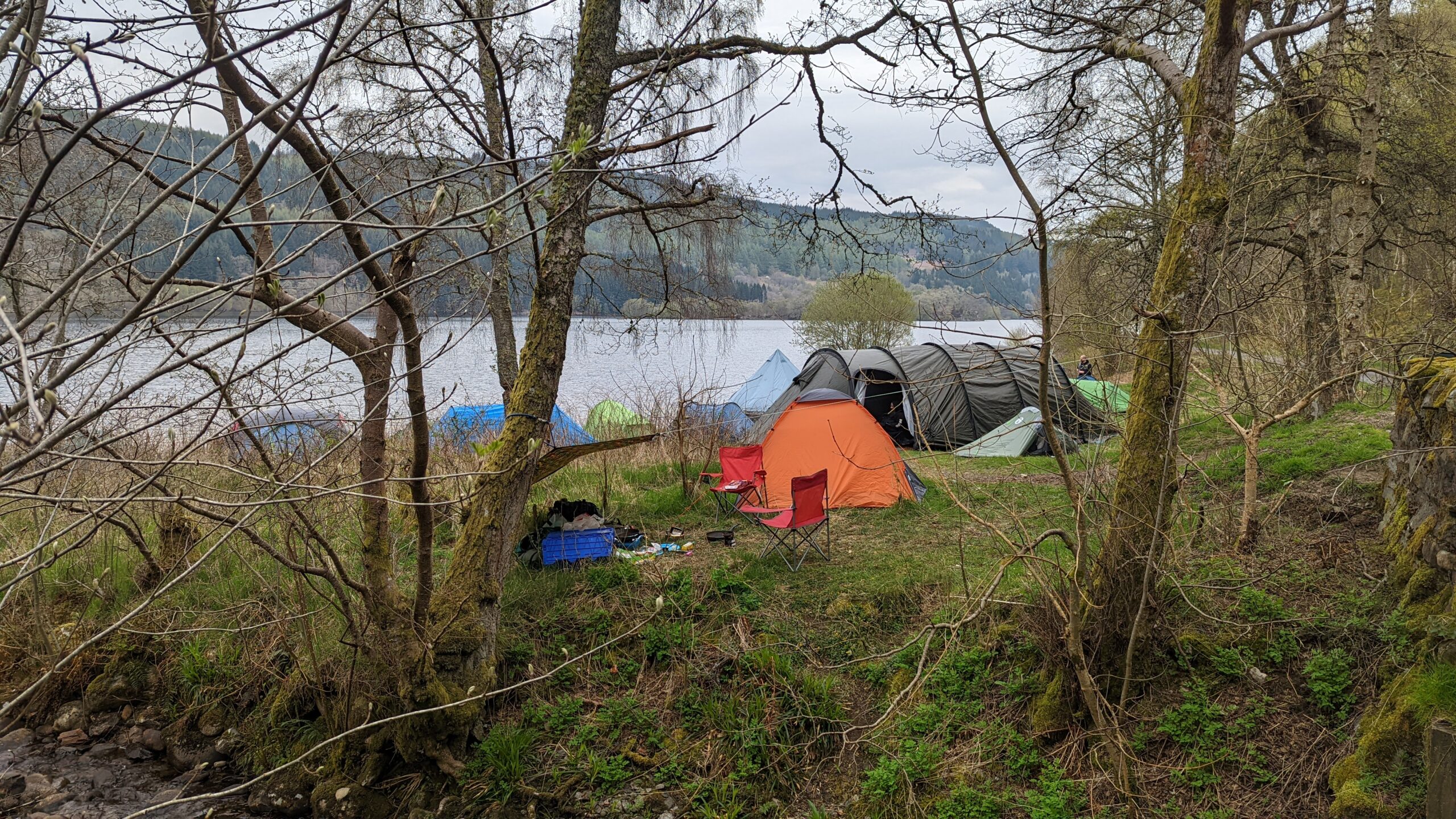 View of a number of large tents, pitched at the side of a loch in Scotland