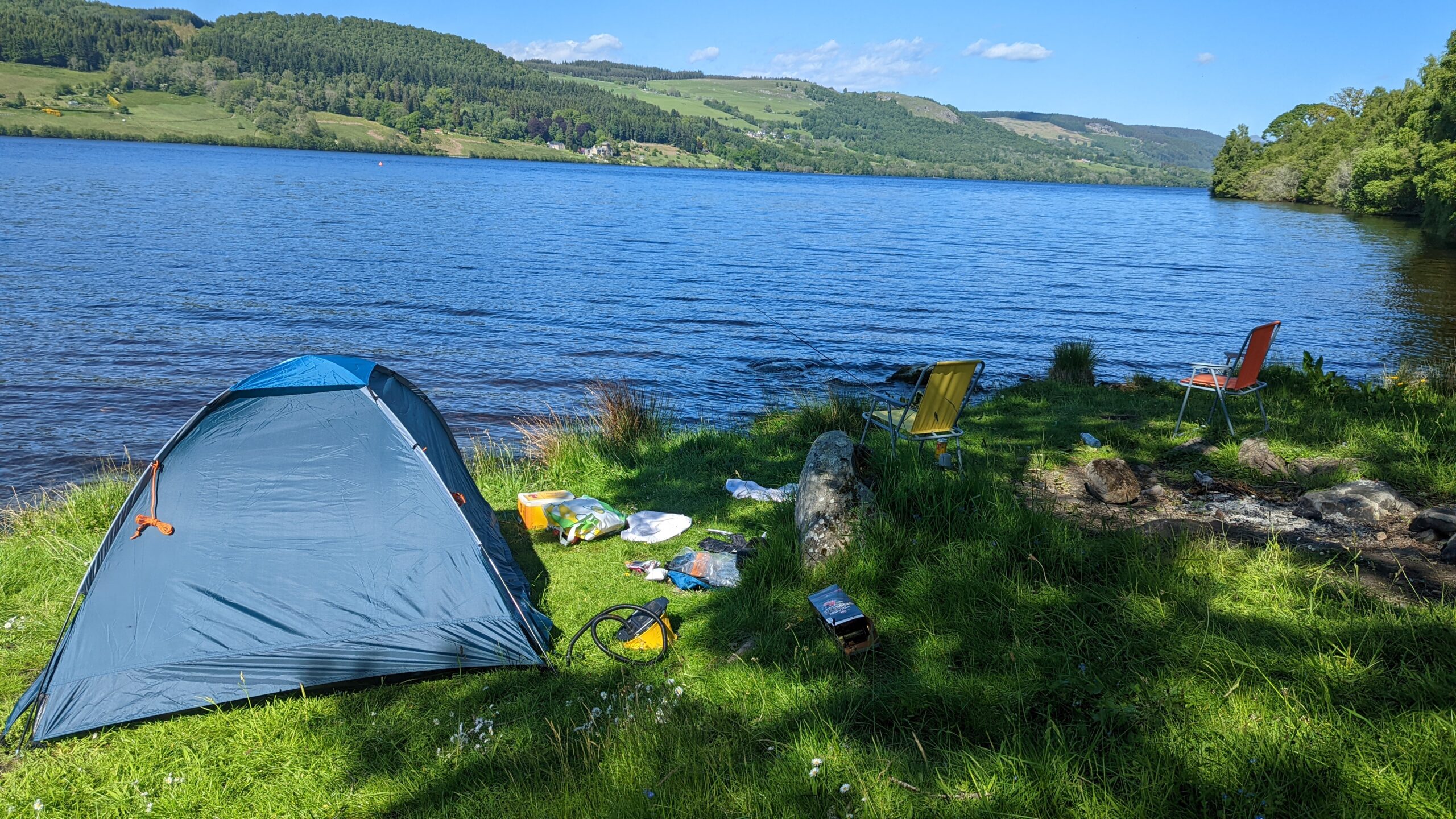 Dirty Camping. A tent pitched beside a loch in Scotland. Rubbish and belongings strewn all around